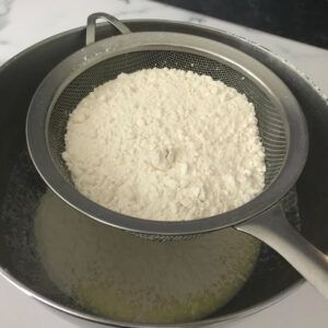 sifting flower over bowl