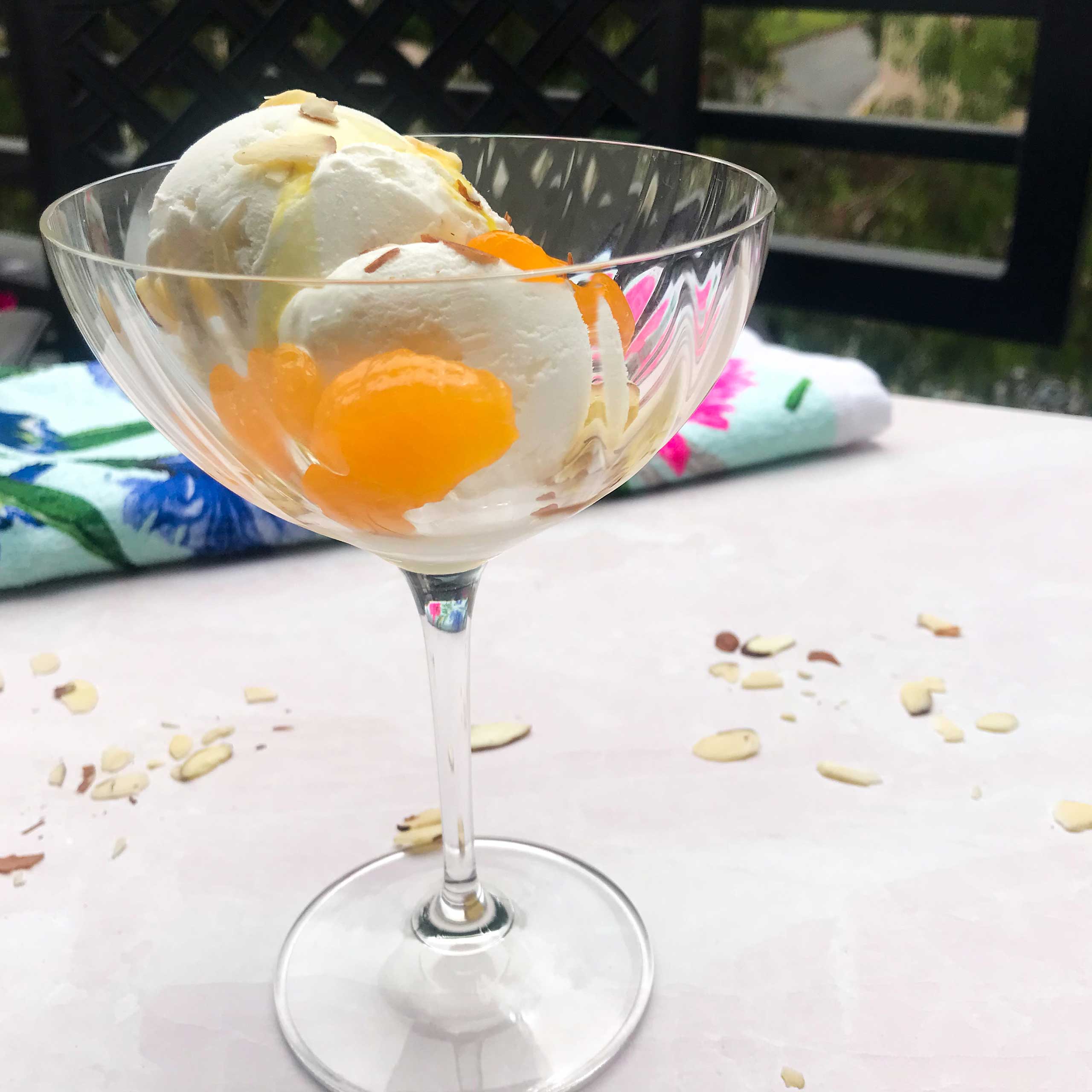 glass with ice cream drizzled with olive oil, mandarin segments and almonds