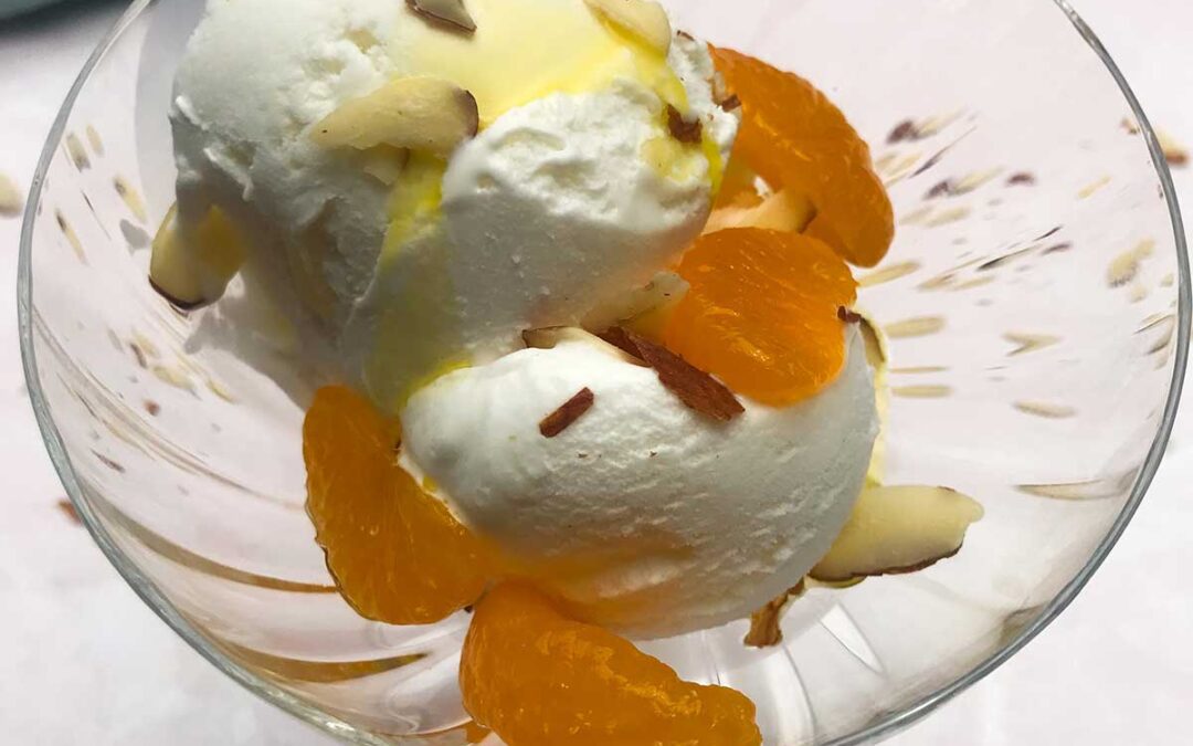 Up close look of ice cream with almonds and mandarin oranges