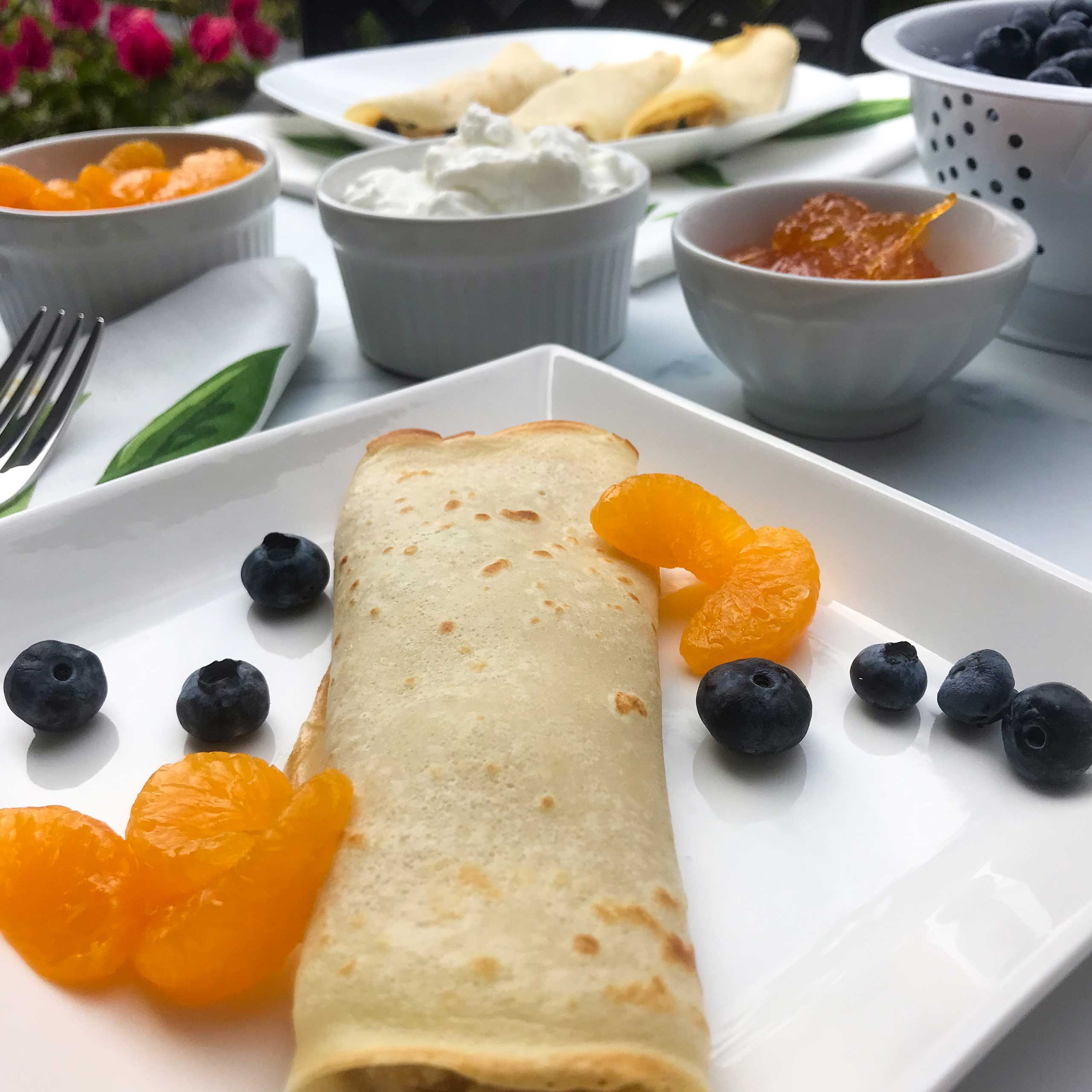 Citrus and Blueberry Blintz on a plate with berries and mandarin sections