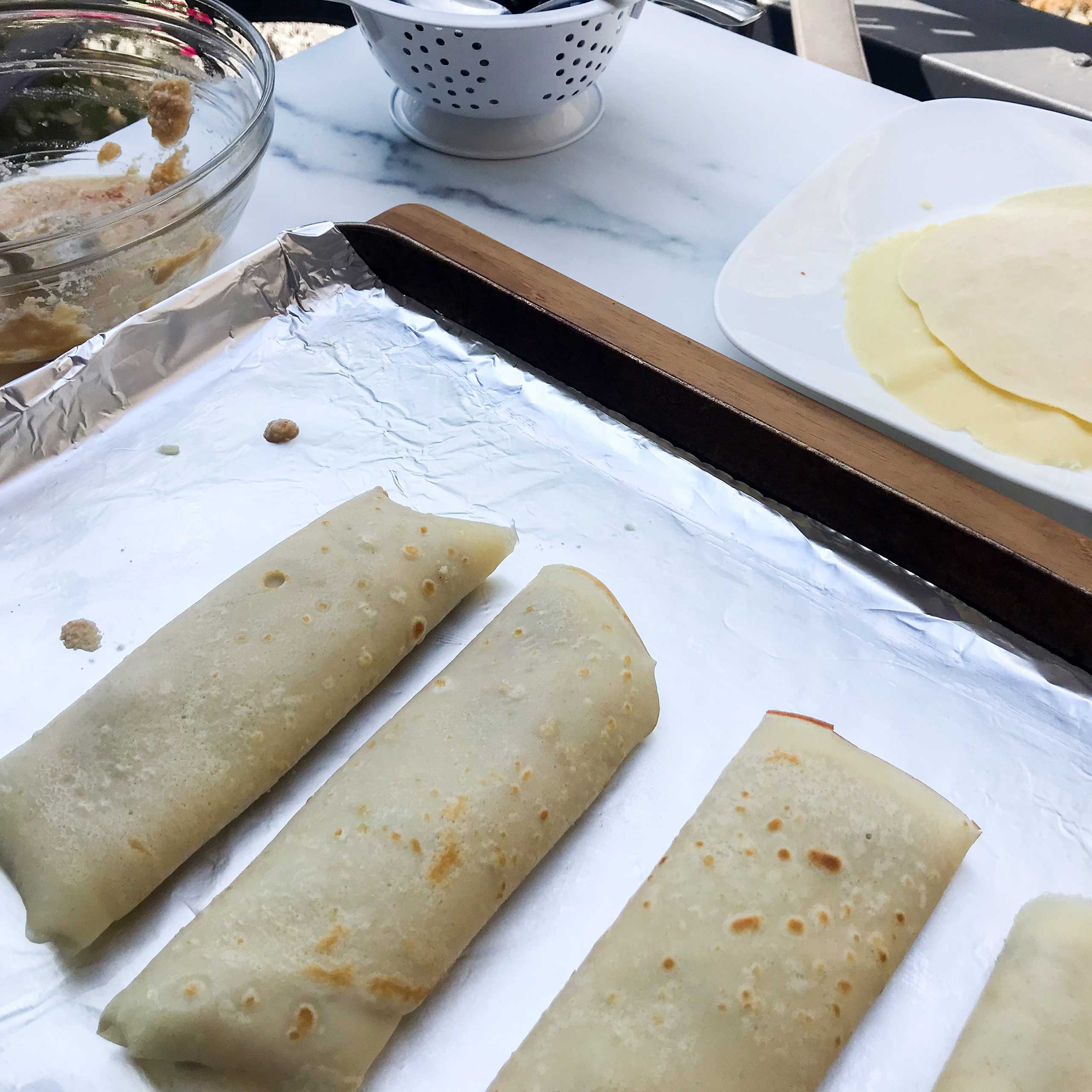 folded and prepared blintzes on a baking sheet