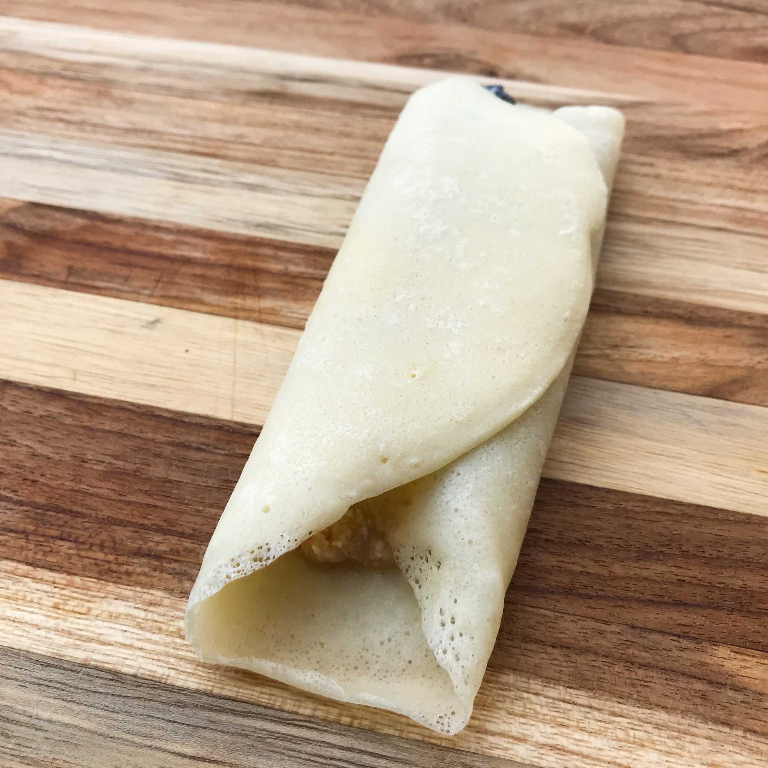 crepe filled and folded sitting on a cutting board
