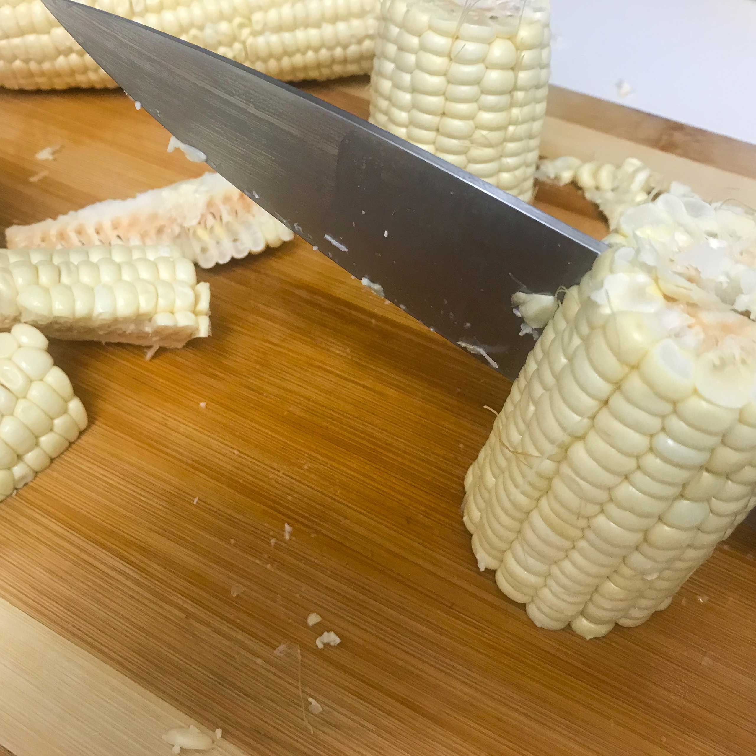 Cut corn cobs on a cutting board with a knife