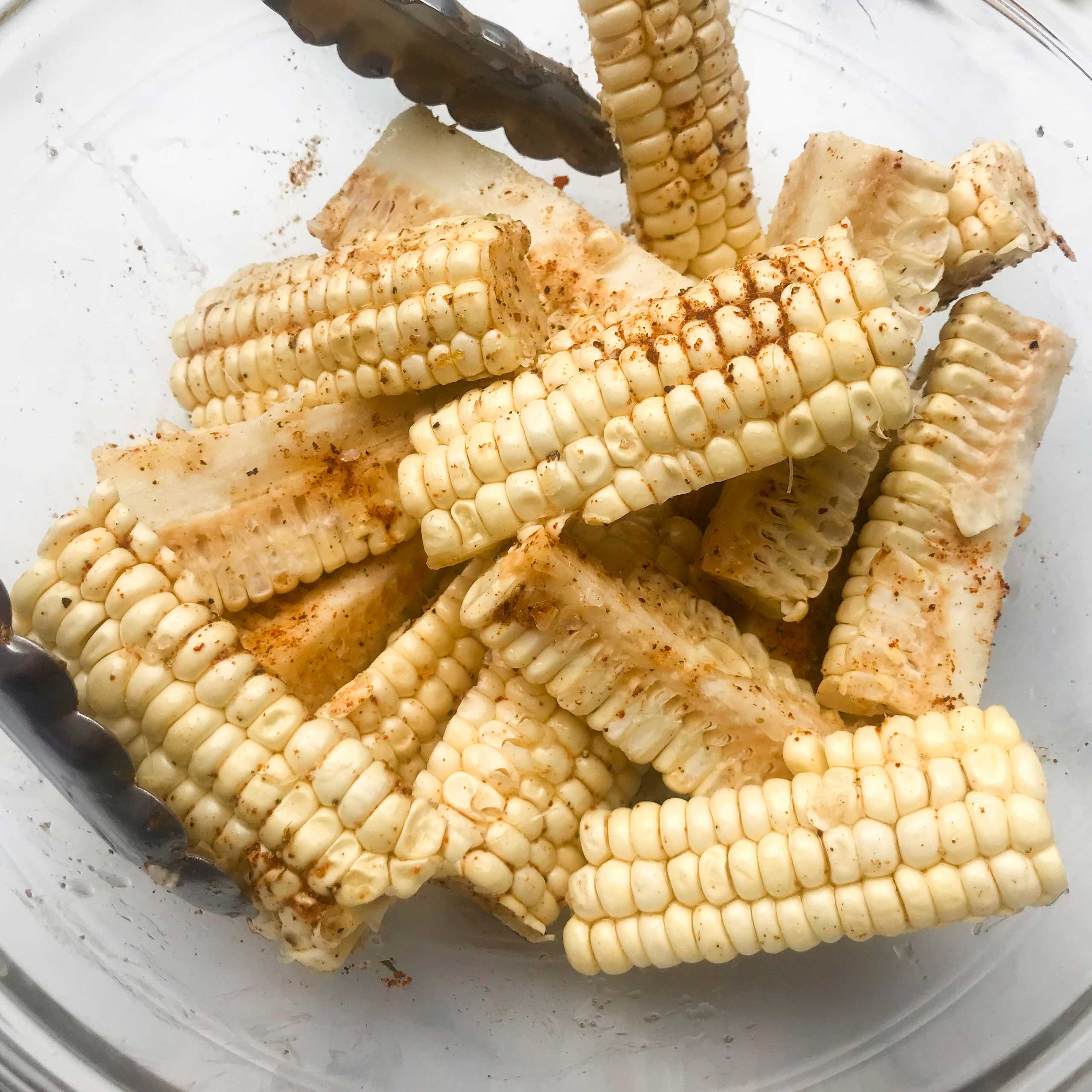 a bowl of corn riblets mixed with oil and seasoning
