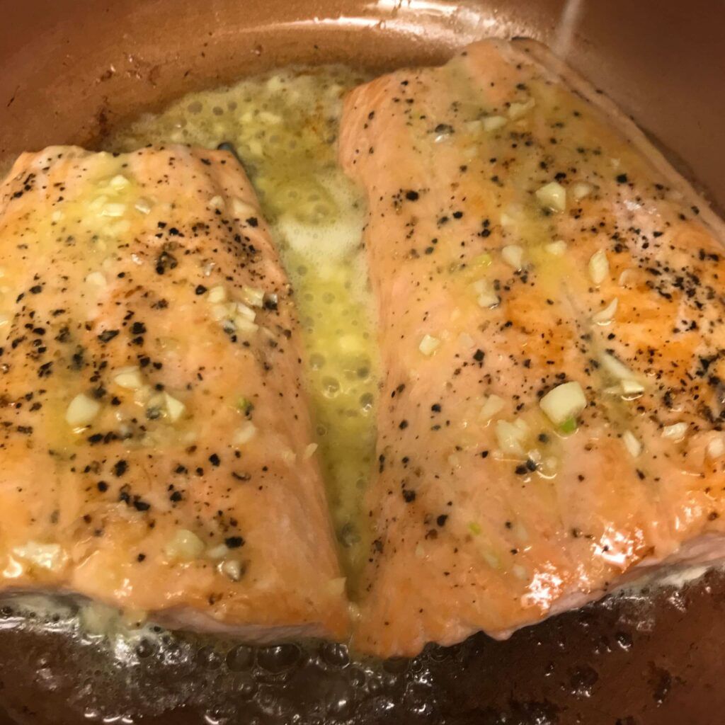 salmon cooking in scampi sauce.