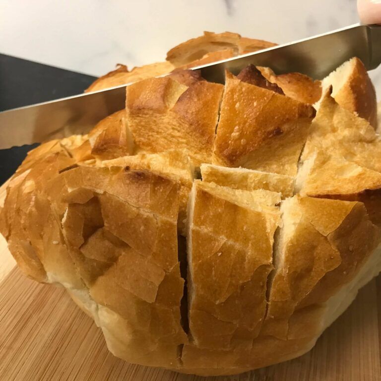 knife slicing a round loaf of bread
