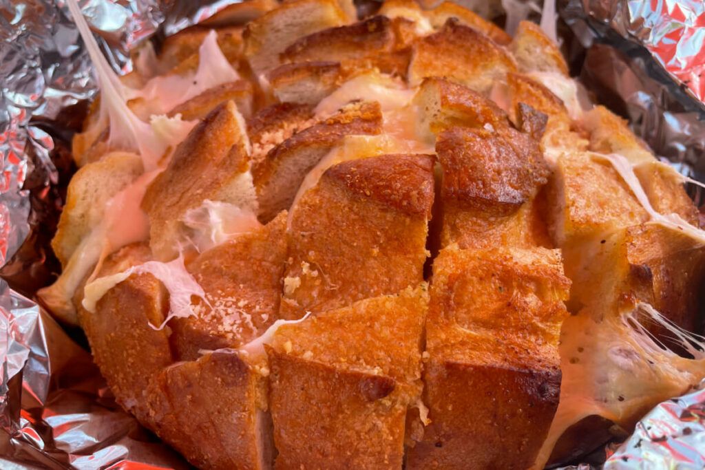 loaf of grilled cheesy bread on foil