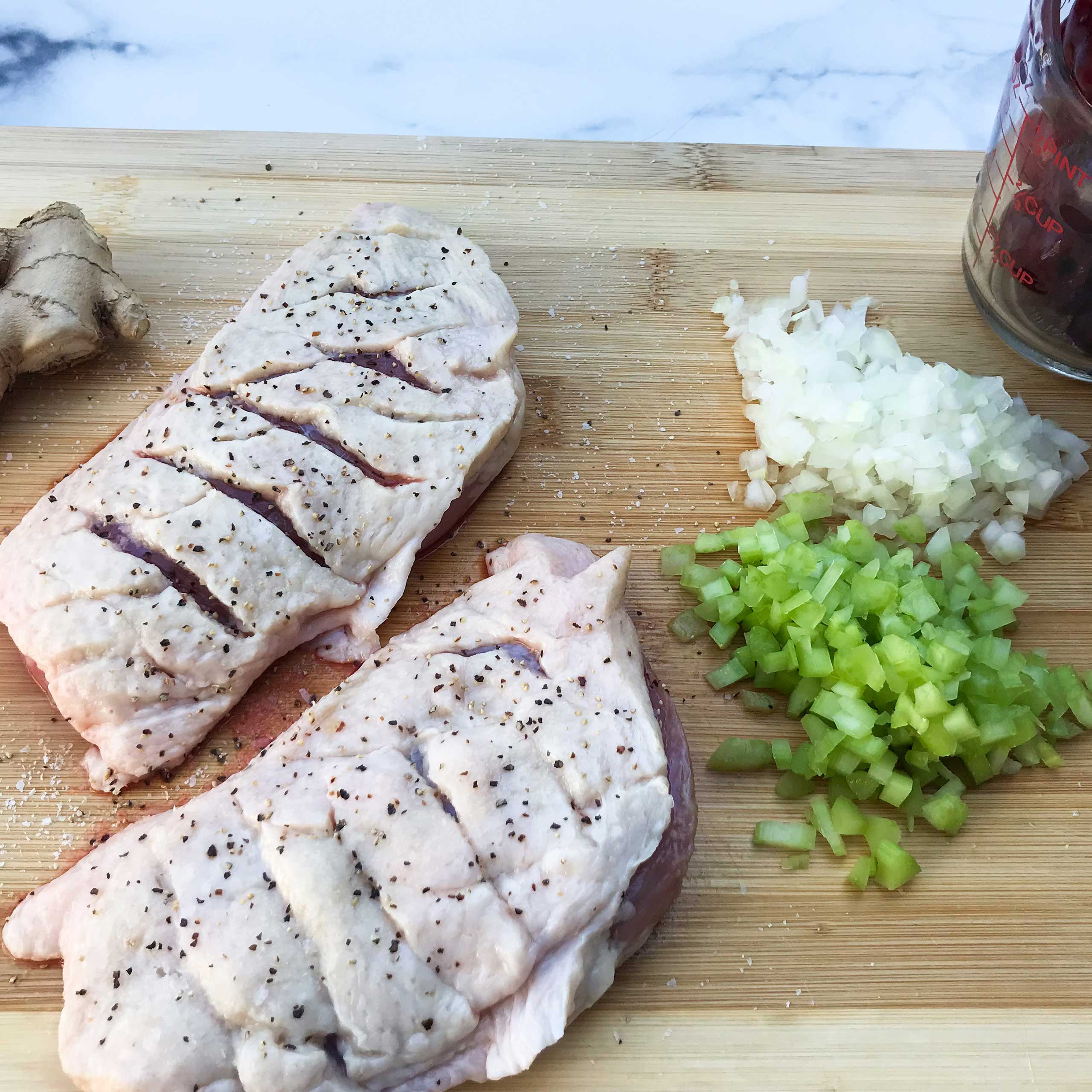 raw duck breasts with diamond pattern slits in skin on board with other ingredients