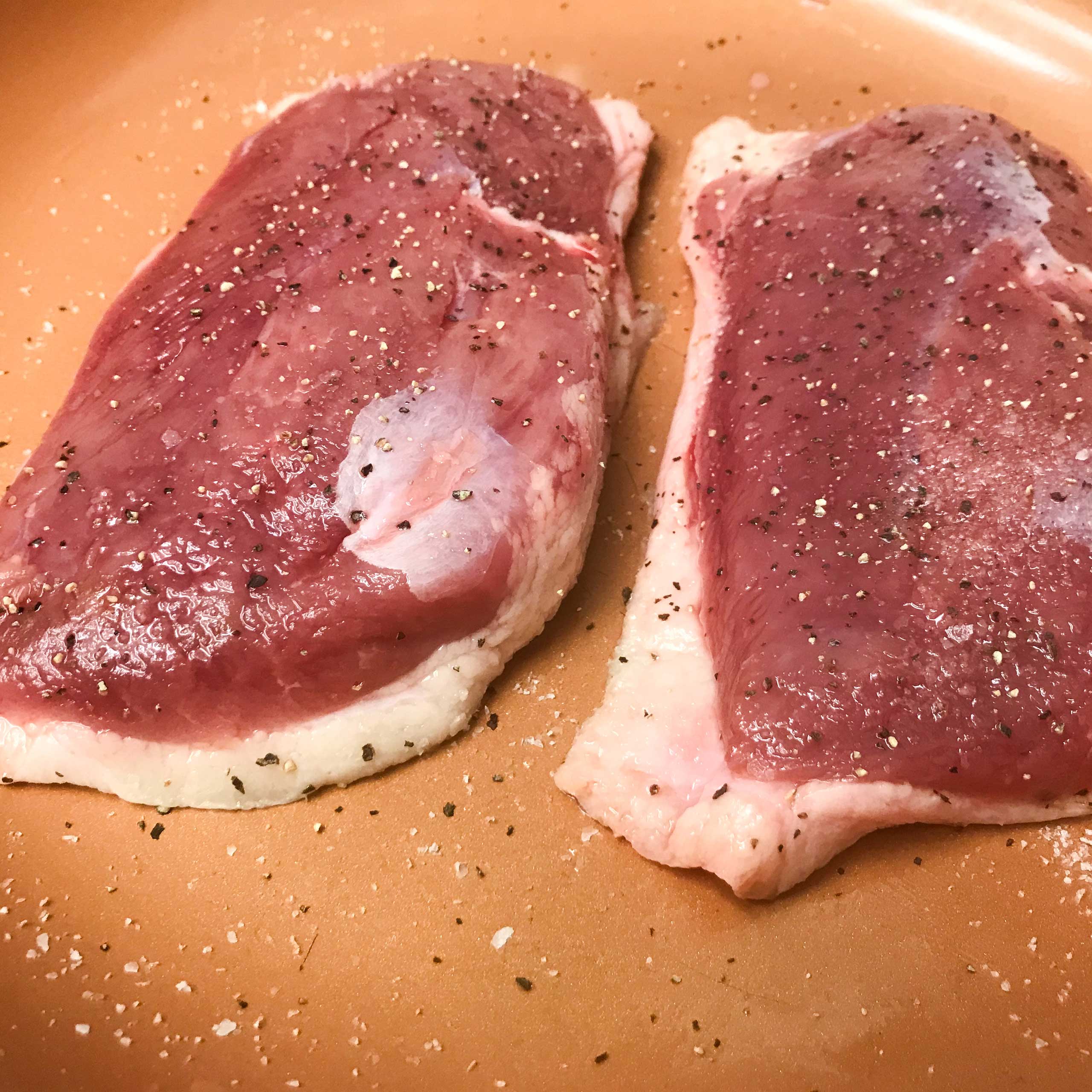 raw duck breasts seasoned and skin side down in skillet