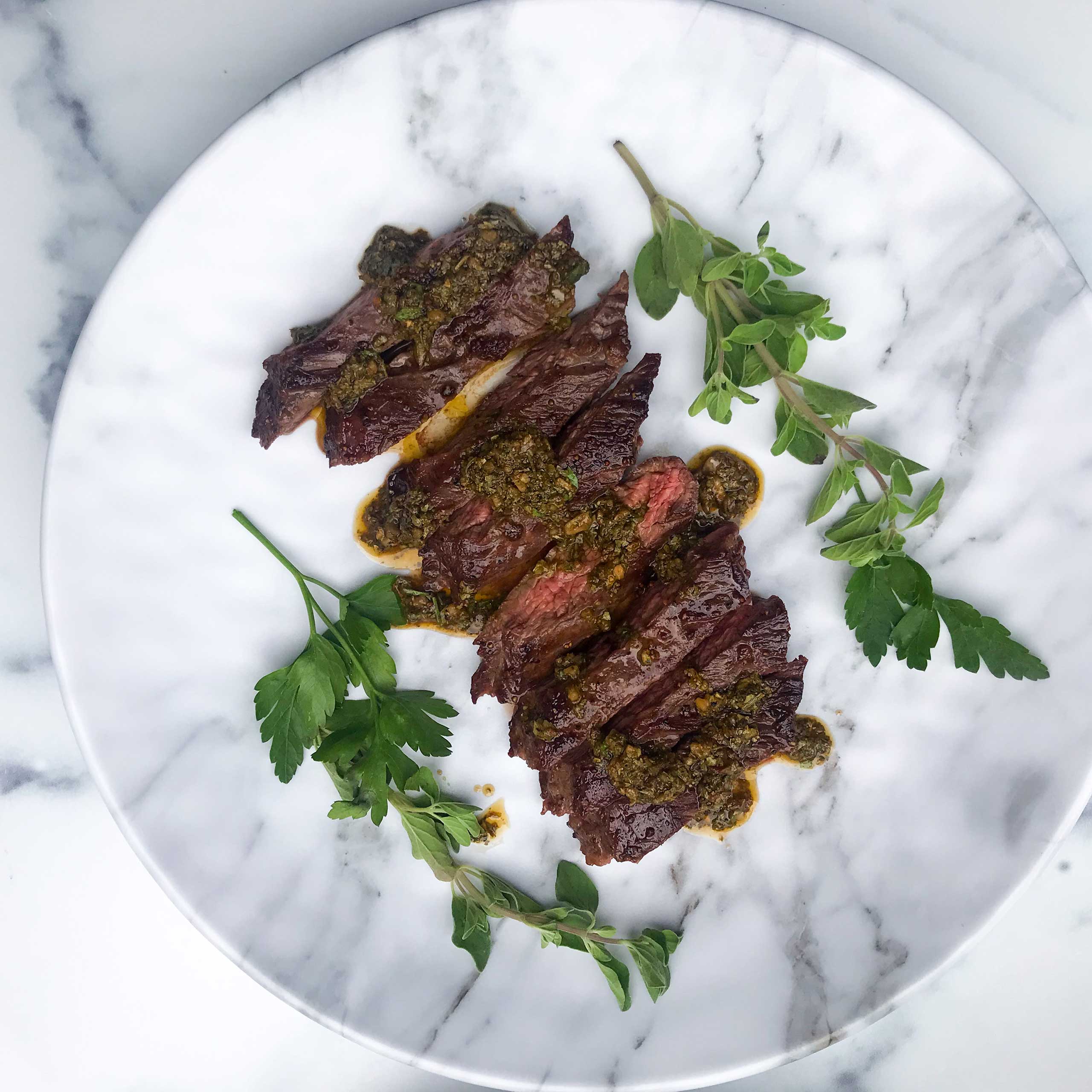 overhead view of skirt steak topped with chimichurri sauce