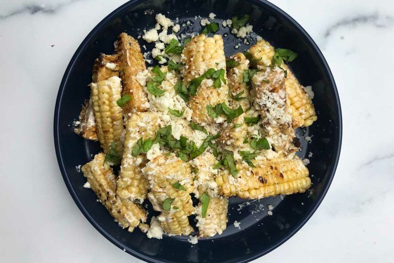 A plate of Elote Corn Ribs (riblets) topped with cheese and herbs
