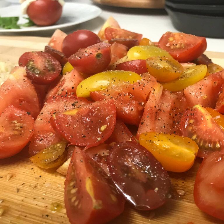 fresh chopped tomatoes on a cutting board with salt and pepper