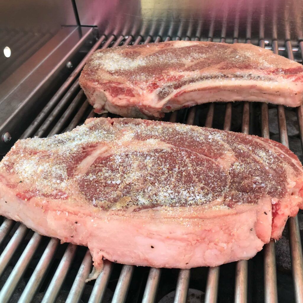 raw rib eyes on the grill.