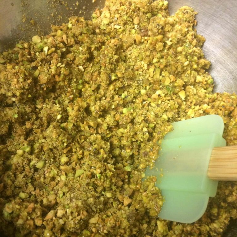 bowl on crushed pistachios and butter being mixed.