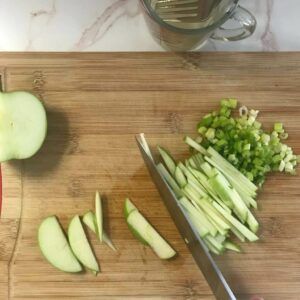 cutting board with sliced apples and chopped green onion.