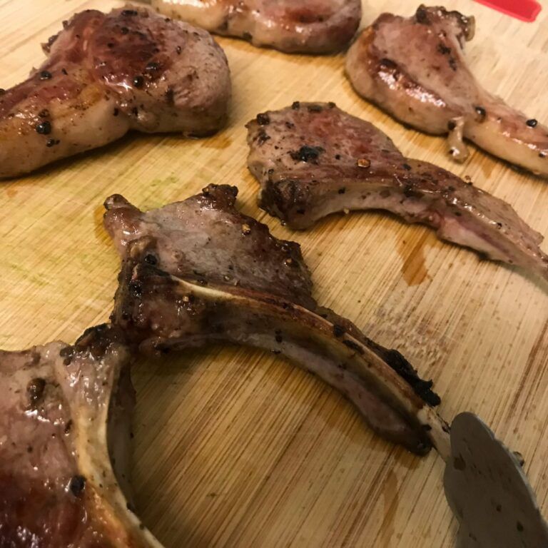 cooked lamb chops resting on cutting board