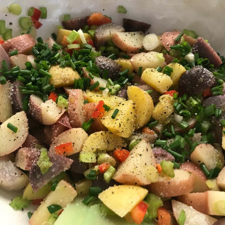 cooked potatoes, veggies, chives and salt and pepper in a bowl