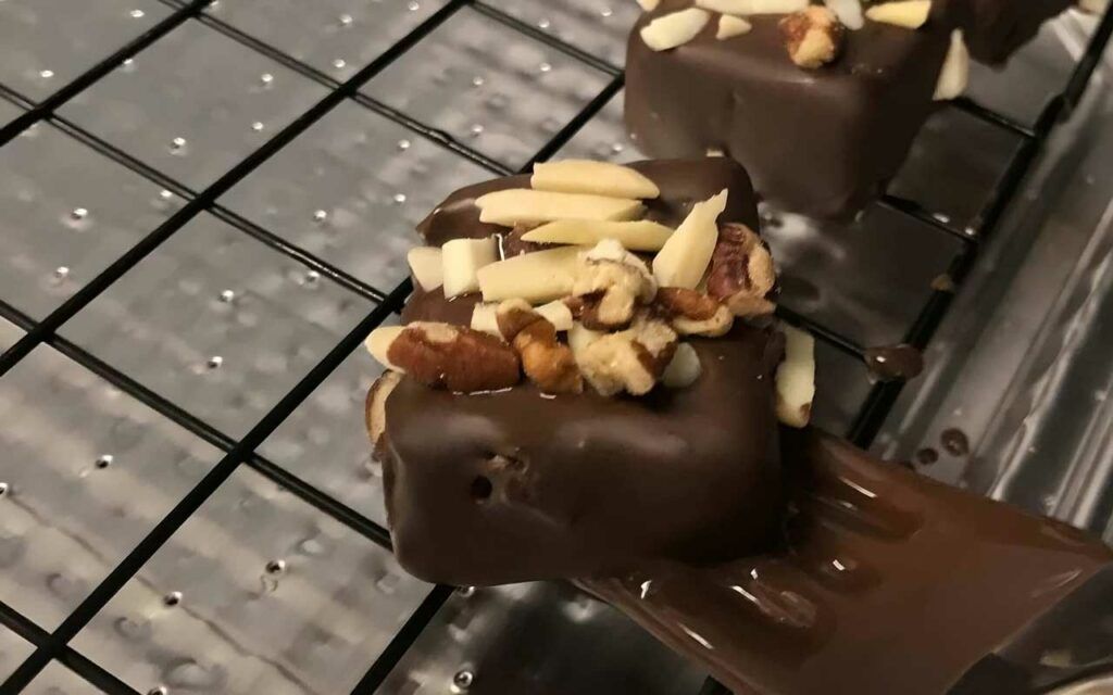 bananas covered in chocolate and nuts on a rack.