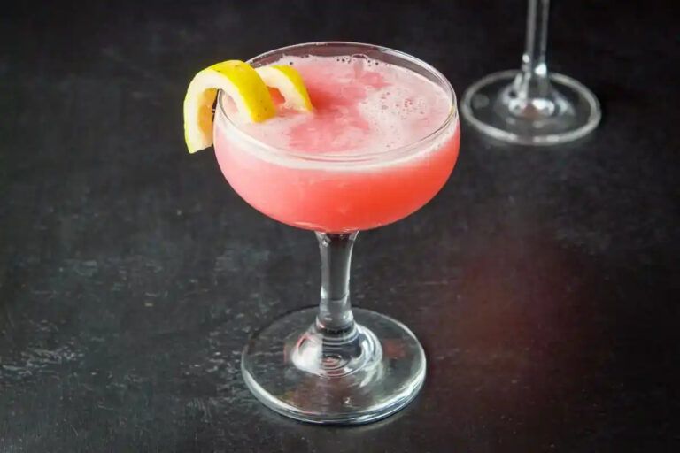 pink lady cocktail in a coup glass with twist of lemon