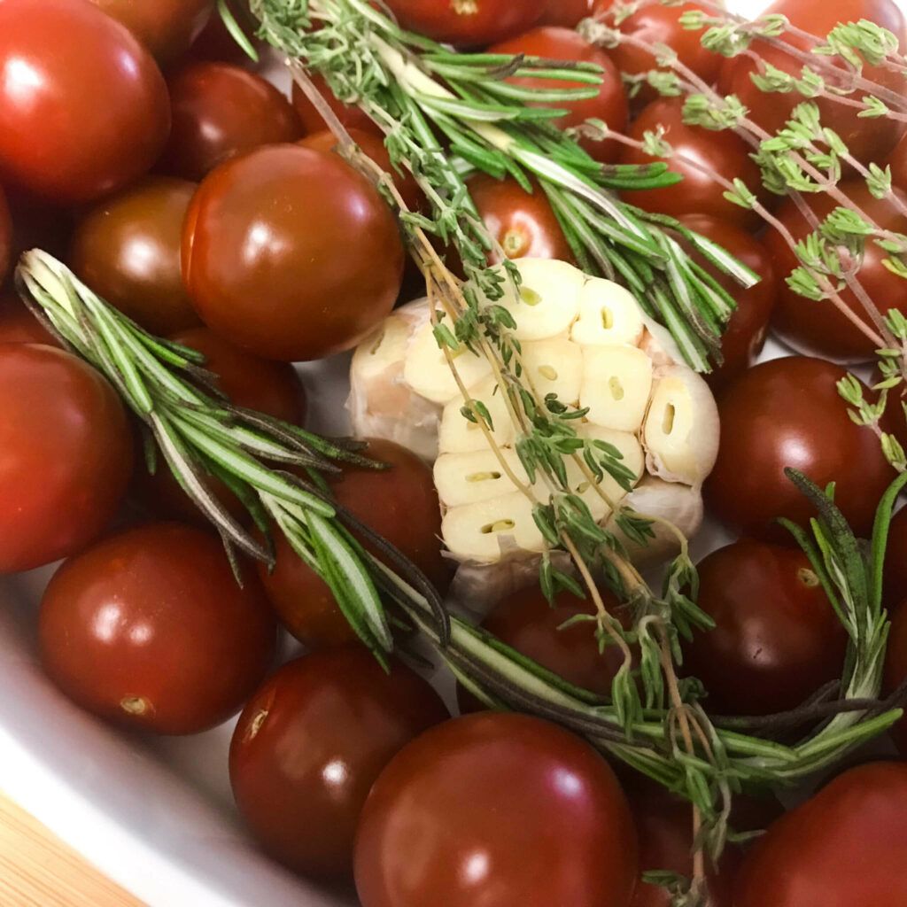 tomatoes, herbs and garlic in baking dish