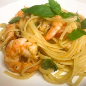 a bowl of plated linguine with shrimp and fresh tomato sauce topped with basil