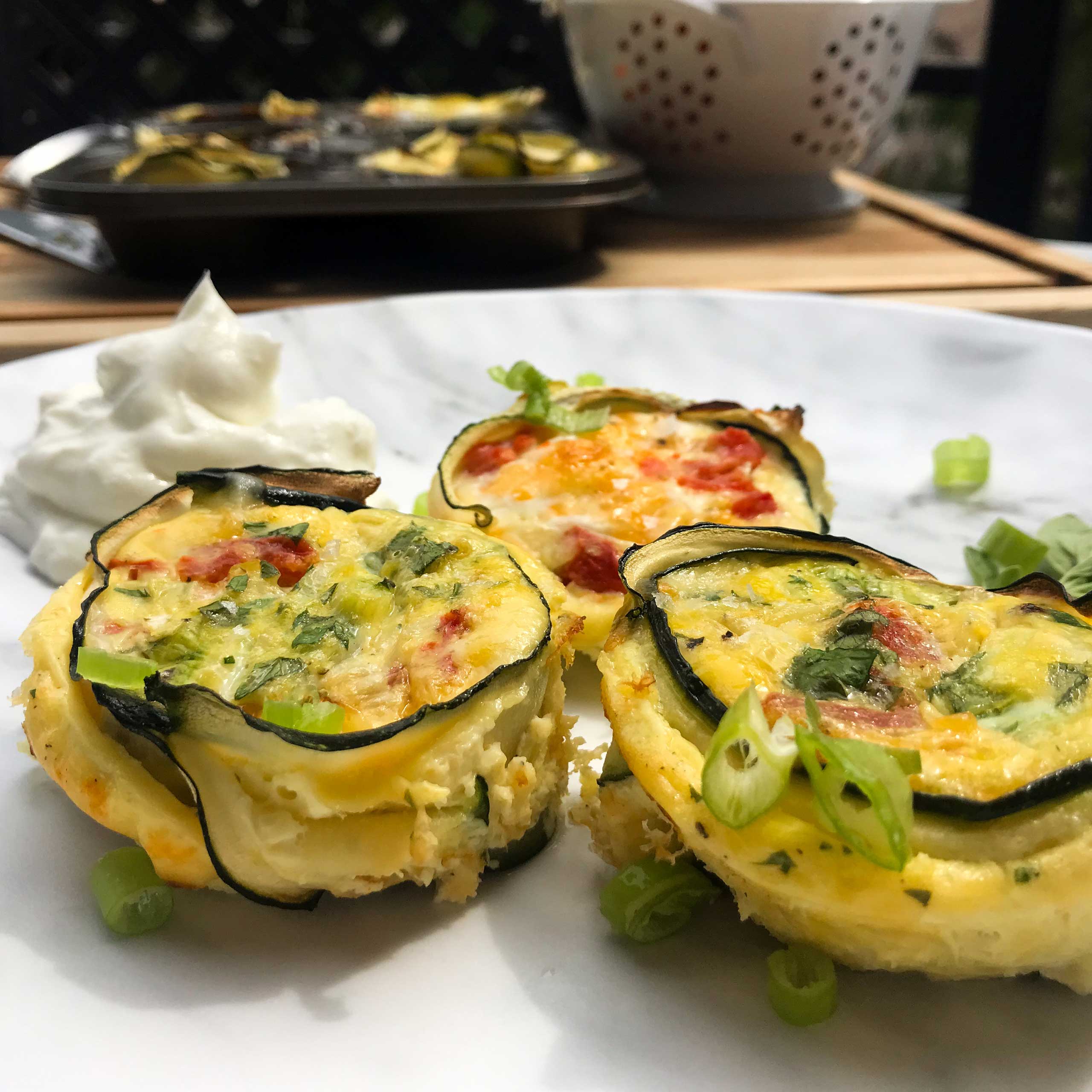 cooked zucchini egg cups on a plate with green onion and greek yogurt