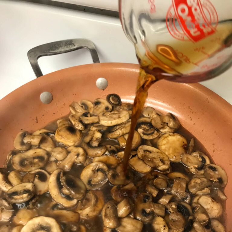 stock being poured into mushrooms in a skillet