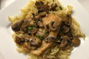 chicken marsala on a bowl of buttered noodles