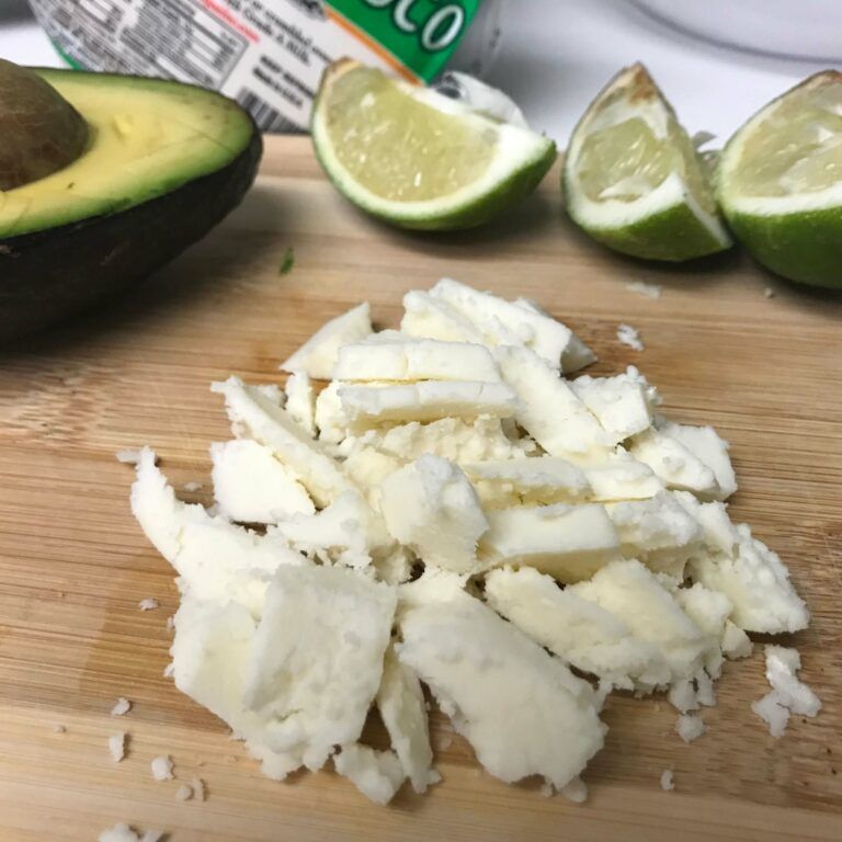 crumbled queso, avocado and cut limes on a board