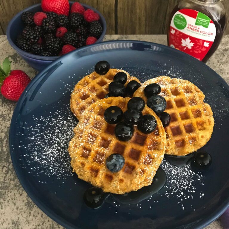 cooked waffles with blueberries and a bowl of berries.