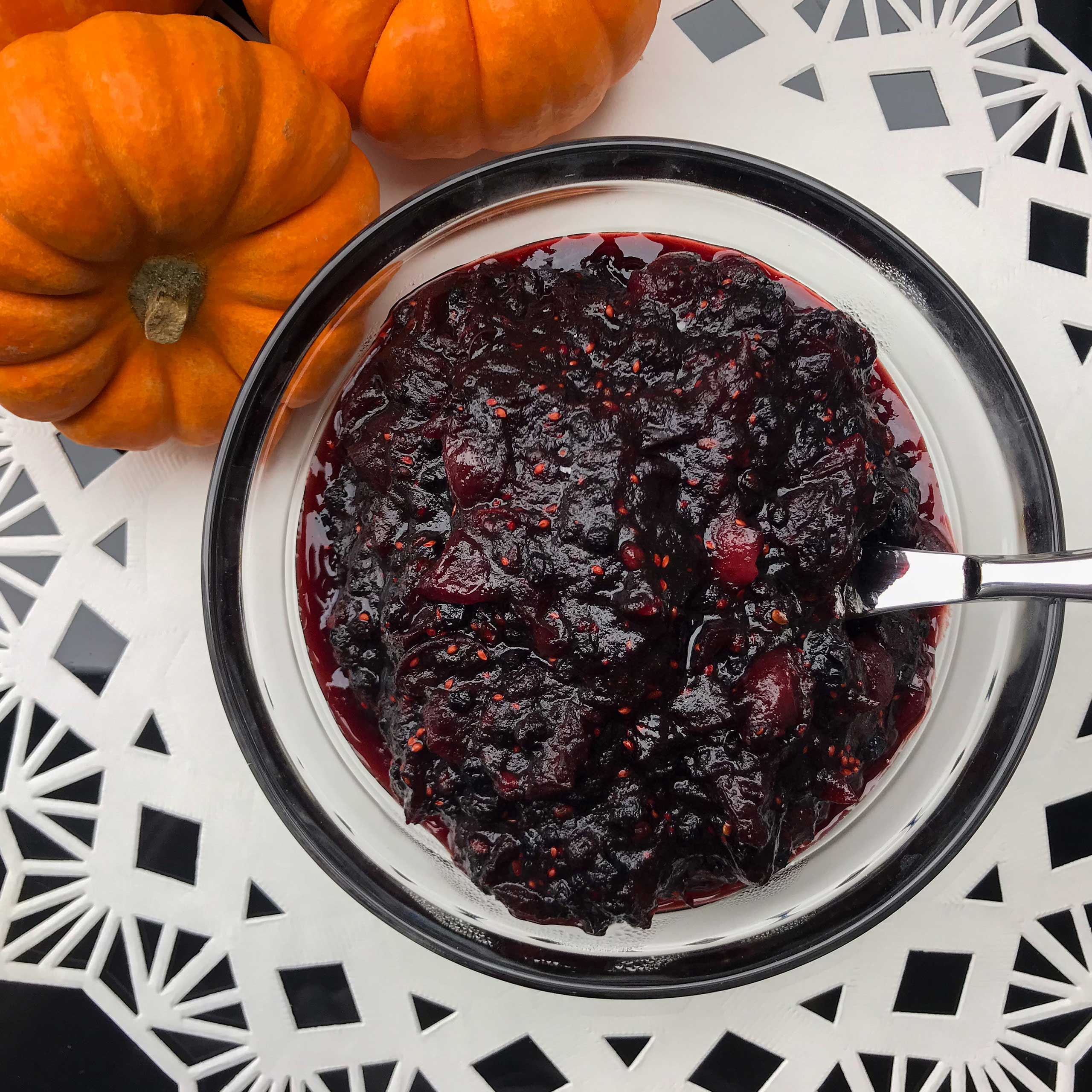 overhead view of bowl of cranberry sauce next to pumpkins
