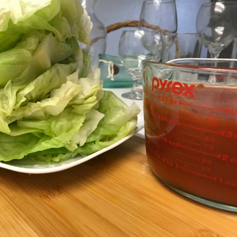 stack of cabbage leaves next to measuring cup of tomato sauce