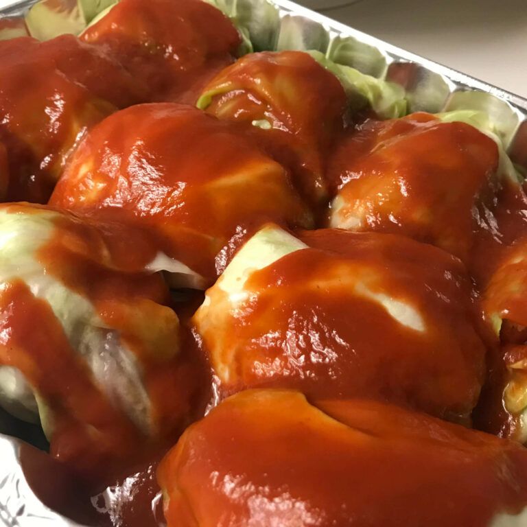 tray of cabbage bundles covered with tomato sauce