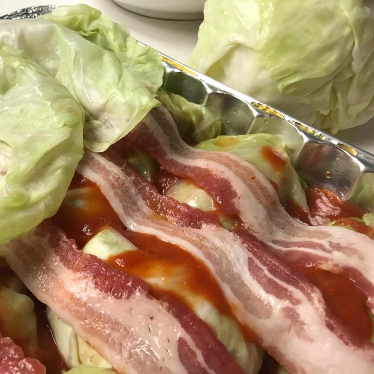 tray of cabbage rolls topped with bacon