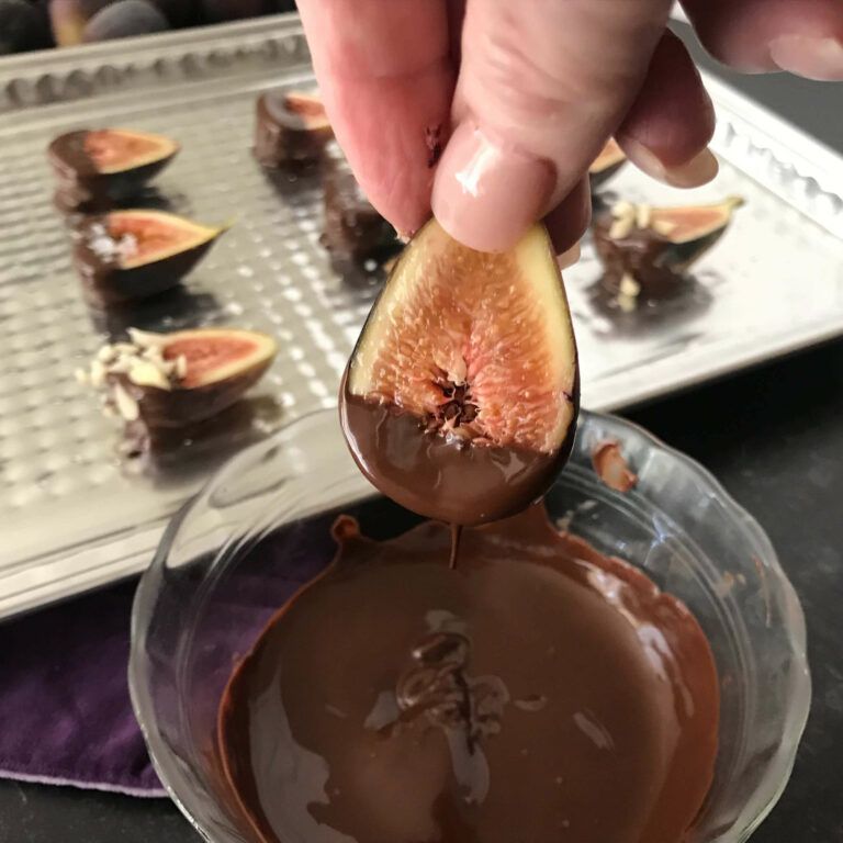 dipping a half a fig in chocolate