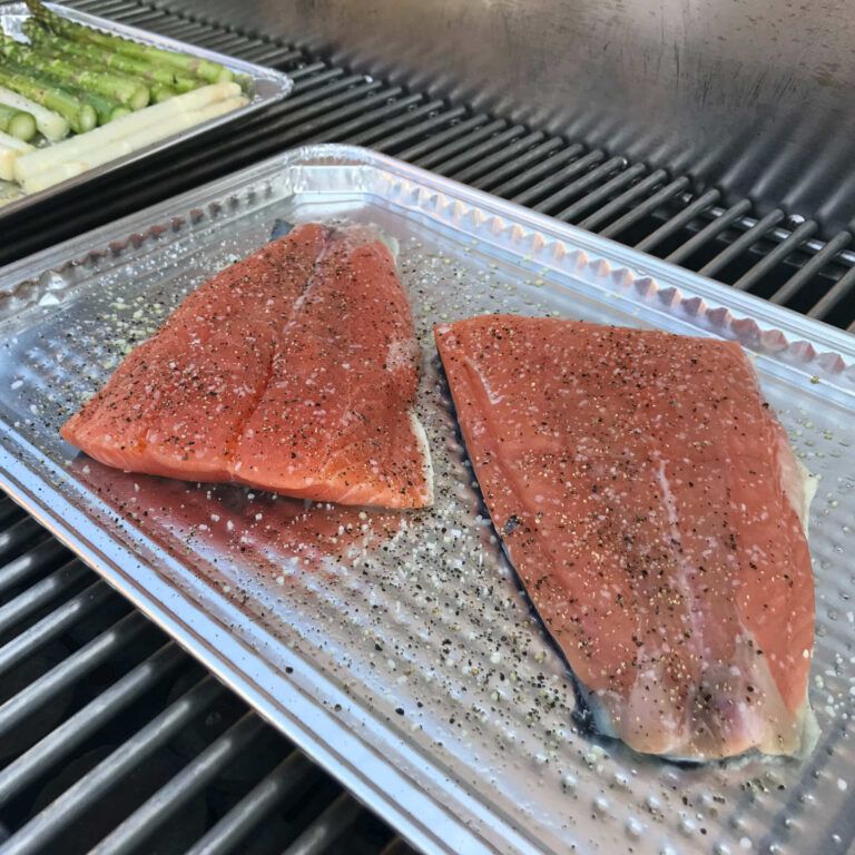raw salmon on a baking sheet on the grill