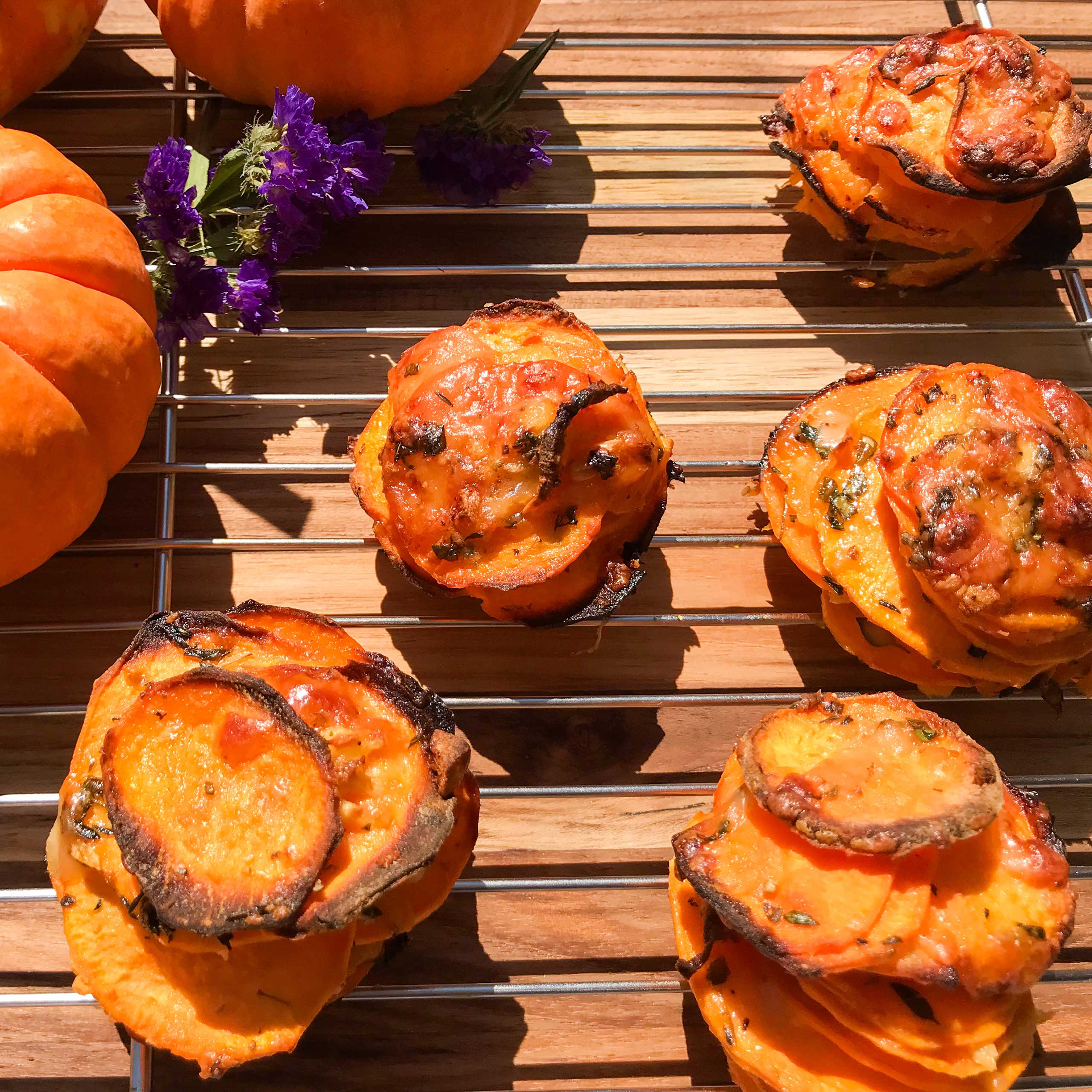 stacks of cooked potatoes on a rack with pumpkins in the background