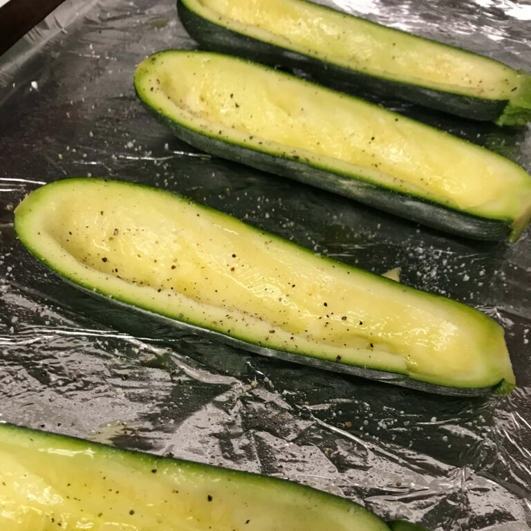seasoned zucchini halves on a baking sheet