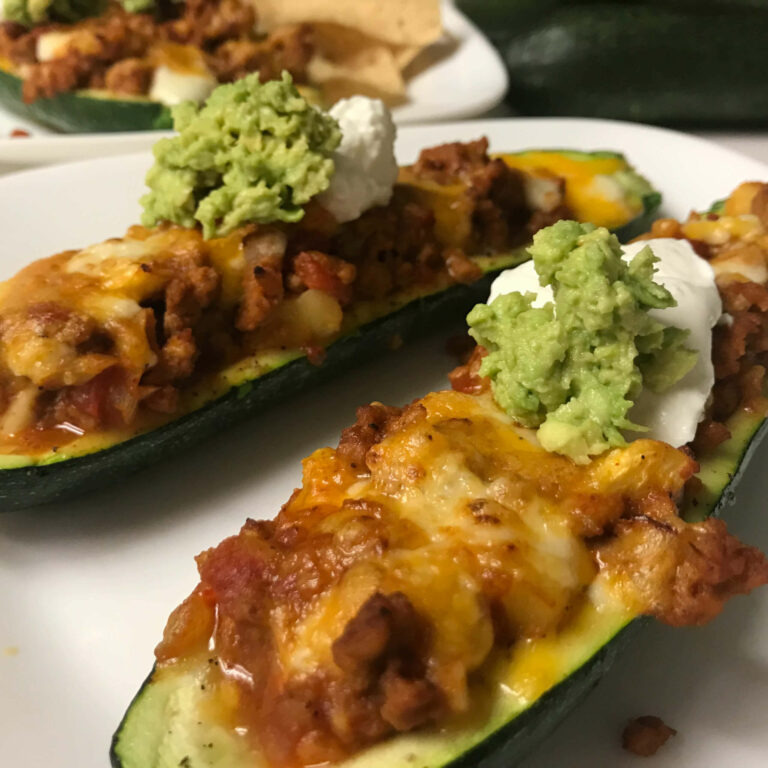 Mexican turkey zucchini canoes on a plate with yogurt and avocado