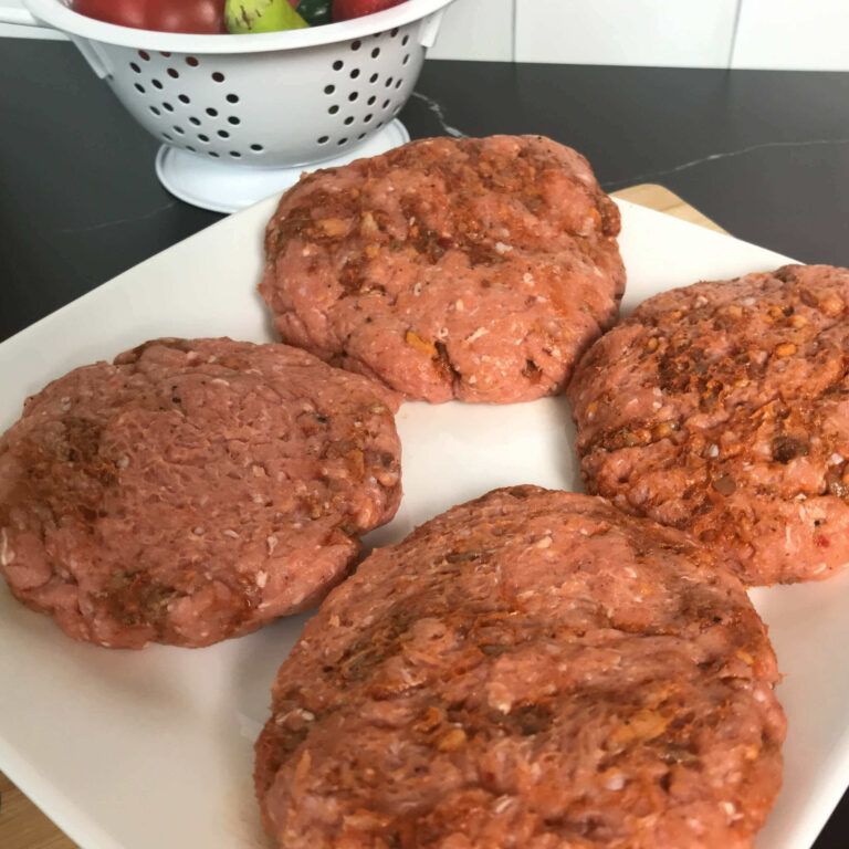 four raw meat patties on a plate