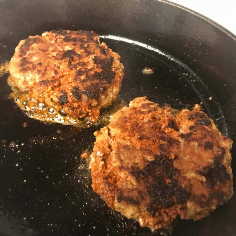 two cooked burger patties in a pan