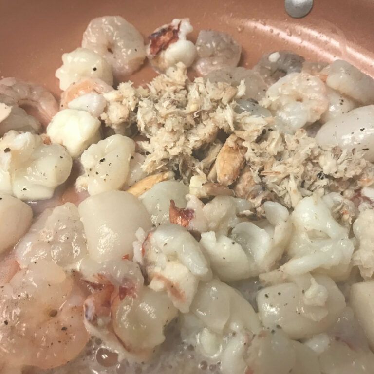 raw seafood and champagne cooking in skillet
