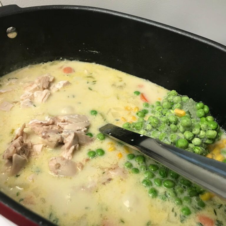 pot of creamy soup with veggies and chicken added