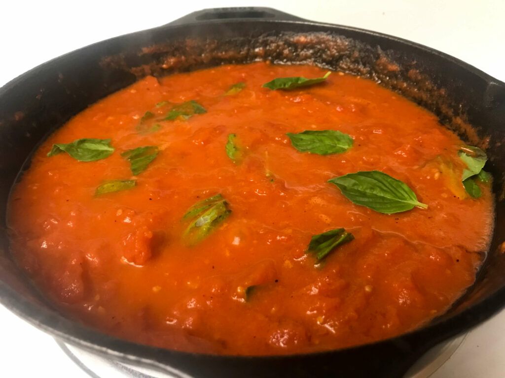 tomato sauce in a skillet with basil