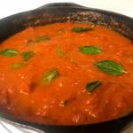 tomato sauce in a skillet with basil