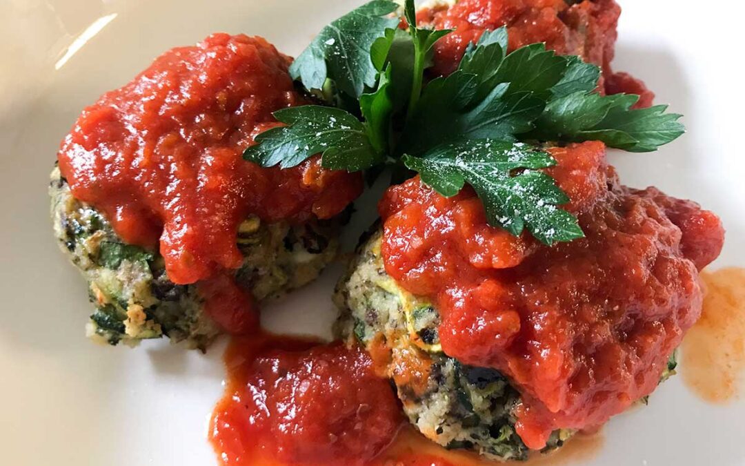 three meatballs topped with sauce and parsley