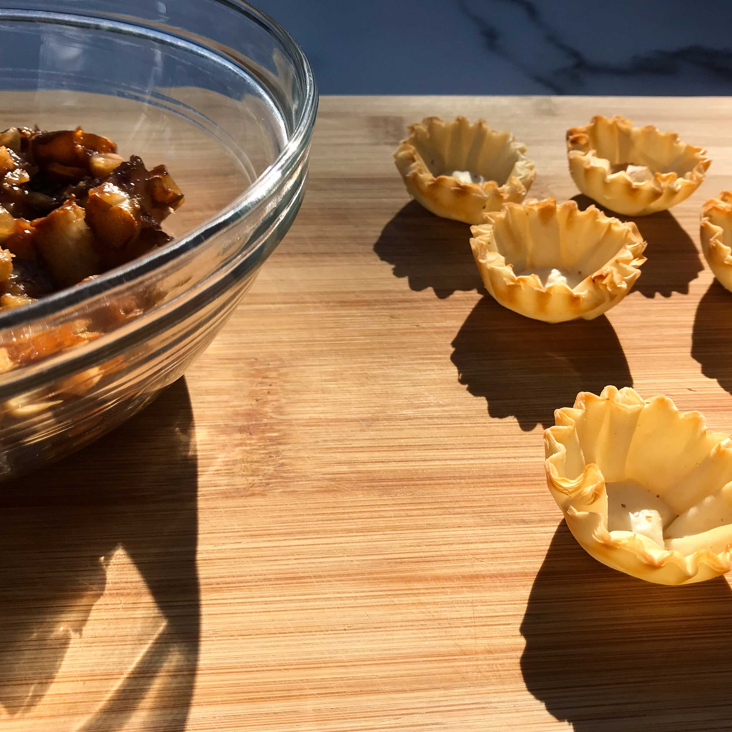 empty phyllo shells next to pears and macadamia nuts in a bowl.