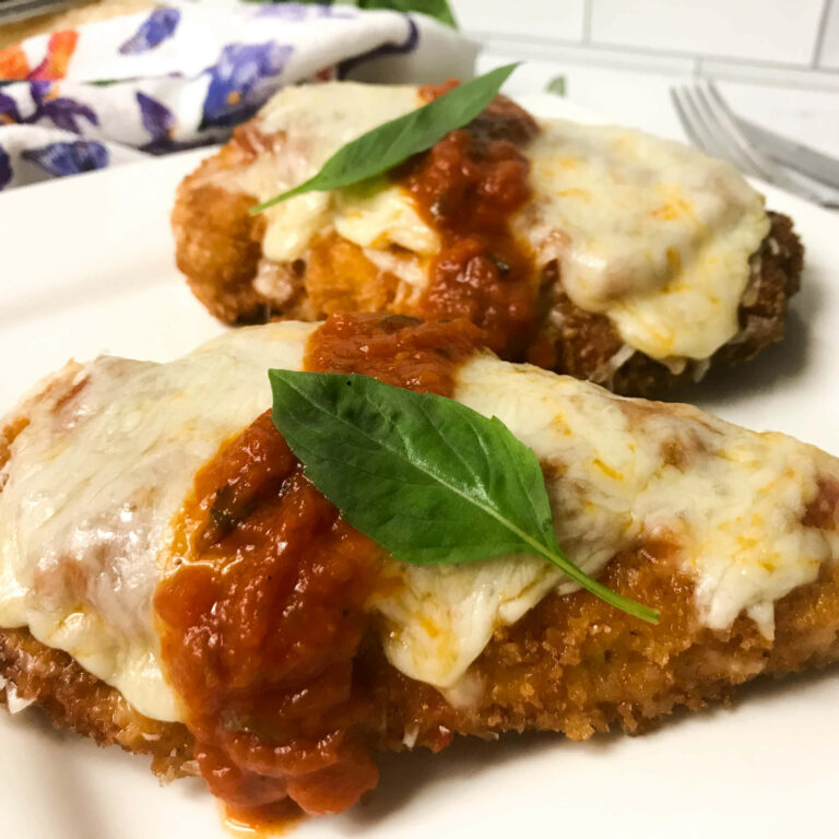 plated chicken parmesan with fresh basil leaves.