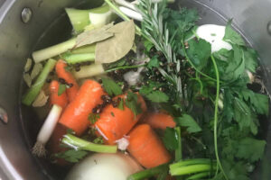 veggies and herbs in a pot.