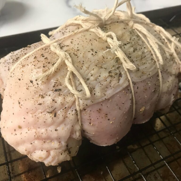 twine wrapped turkey breast on a rack in a roasting pan.
